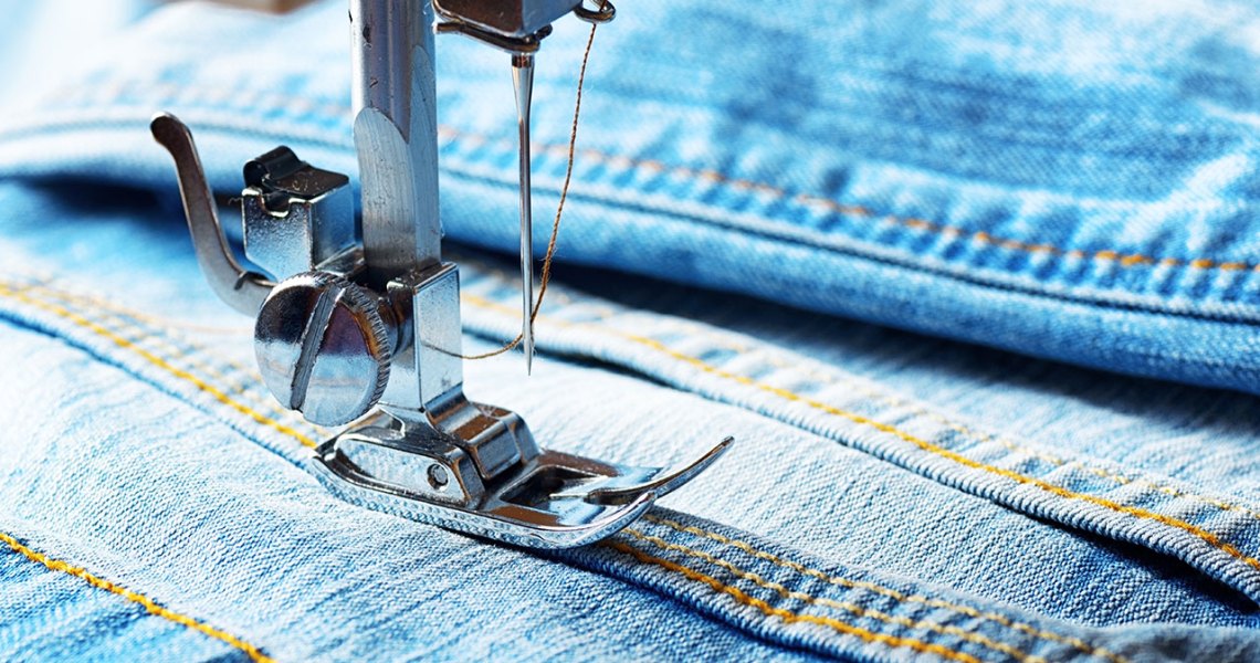 Photograph of a sewing machine needle and denim fabric.