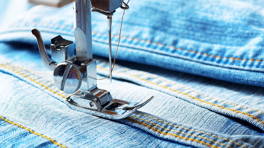 Photograph of a sewing machine needle and denim fabric.
