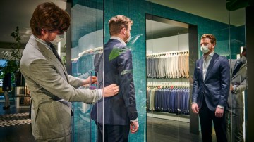 Photograph of a man being fitted for a suit.