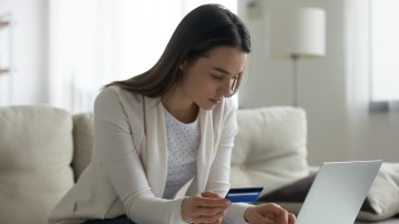 Woman typing on laptop holding credit card using secure payment