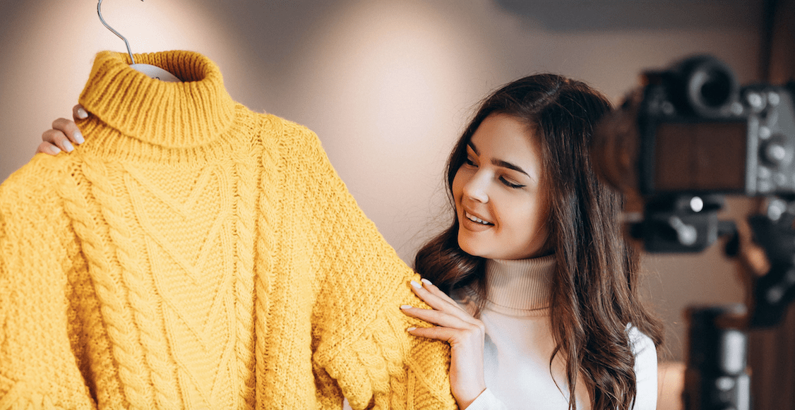 Photograph of a woman holding up a yellow sweater.